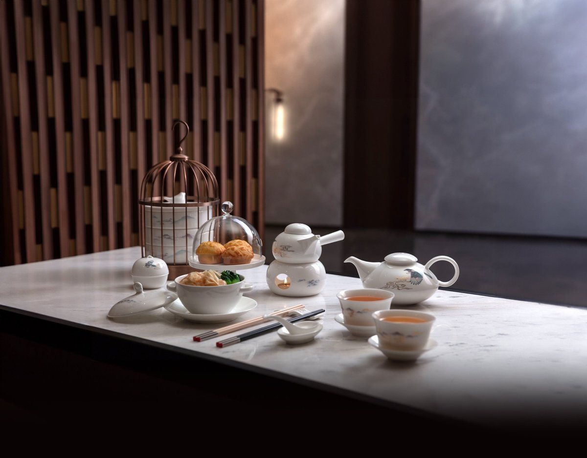 Private dining and lounge suite at HKIA VIP Lounge featuring a formal round dining table set with fine china, plush seating, ambient lighting, and a separate luxury living area with modern art.