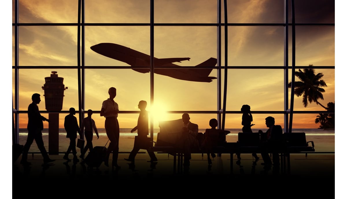 Silhouettes of travelers at an airport terminal with a plane taking off at sunset, tropical palm trees, and control tower in the background