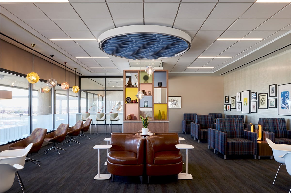 Seating area at the T4 escape lounge at PHX Airport, featuring a mix of stylish leather armchairs, plaid fabric chairs, and modern white swivel chairs.