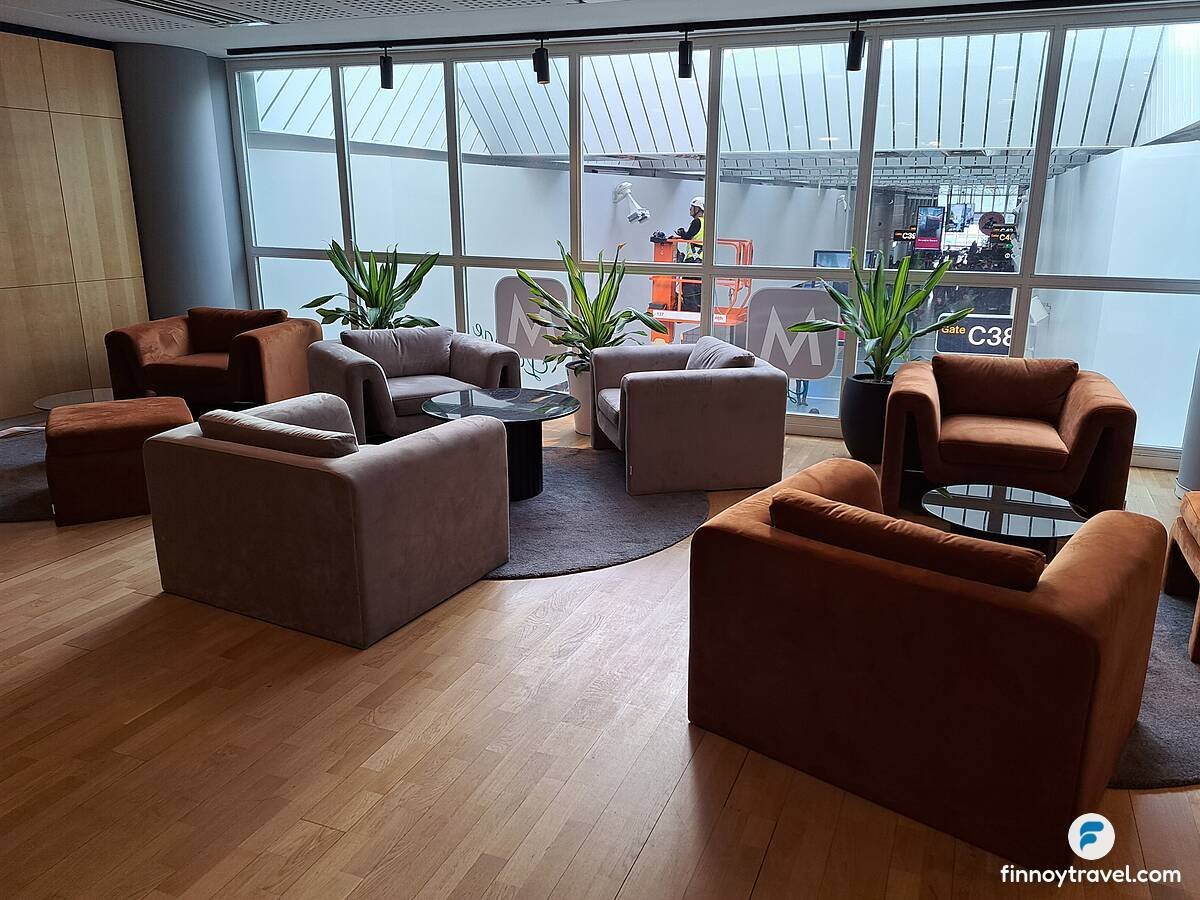 Pearl Lounge seating area at Stockholm Arlanda Airport Terminal 5 near Gate C37, featuring plush rust-orange and grey armchairs arranged around glass coffee tables
