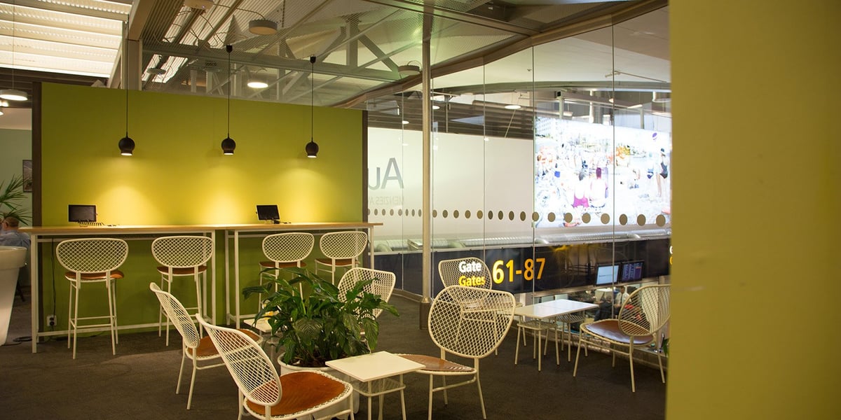 Pearl Lounge Terminal 2 at Stockholm Arlanda Airport – bright seating area with white mesh chairs, brown leather cushions, small tables, and a lime green feature wall