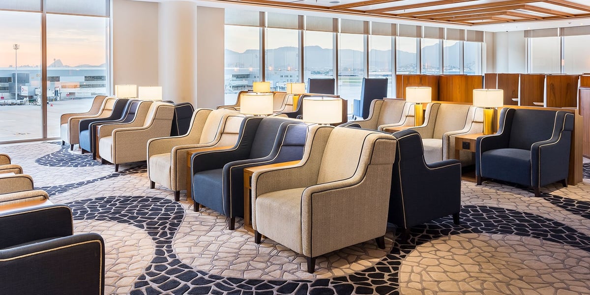 Spacious seating area inside Plaza Premium Lounge at GIG Airport's international terminal, featuring plush armchairs, soft lighting, panoramic runway views, and a stylish carpeted interior with floor-to-ceiling windows.