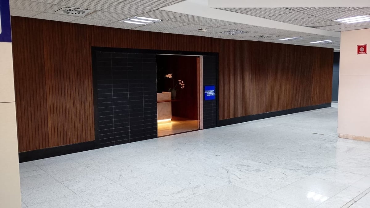Entrance to the 5th Avenue Lounge – W Premium at São Paulo GRU Airport, featuring a sleek design with dark tiles, wooden panel walls, and a softly lit reception area visible through the doorway.
