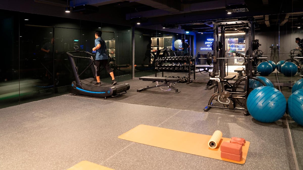 Modern gym facility inside Capsule Transit MAX at KLIA Terminal 2, featuring a treadmill, weight rack, strength training equipment, yoga mats, and exercise balls in a sleek, mirrored workout space.