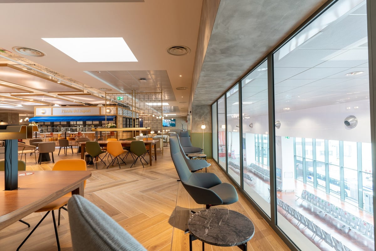Seating and table areas nearby terminal windows at Milan HelloSky Lounge