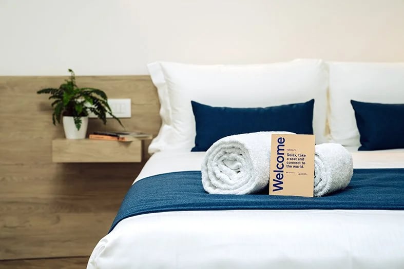 Bed with welcome card at HelloSky Air Rooms at HelloSky Airport Lounge Fiumicino