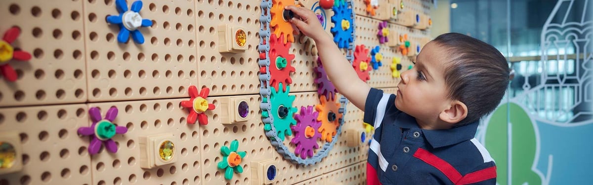 A child engaging with a colourful interactive wall in the playroom of Helsinki's airport at the Plaza Premium Lounge.