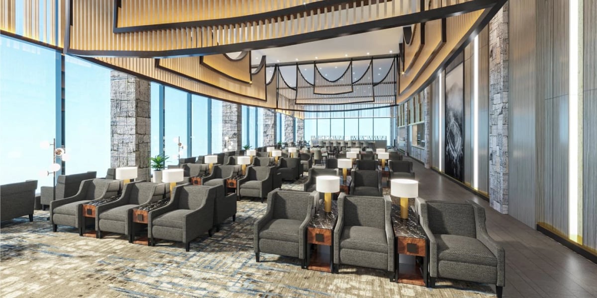 Large seating area in the Jakarta Sapphire Plaza Premium Lounge featuring grey toned sofas with lamps positioned between chairs. The ceiling is high and decorative, the space illuminated with plenty of light from the expansive windows.