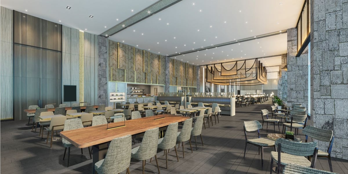 Dining area at the Jakarta Sapphire Plaza Premium Lounge. The seating ranges from elongated wooden tables suited for large gatherings to smaller round tables with three chairs positioned around them. The ceilings are high, the tone contemporary.