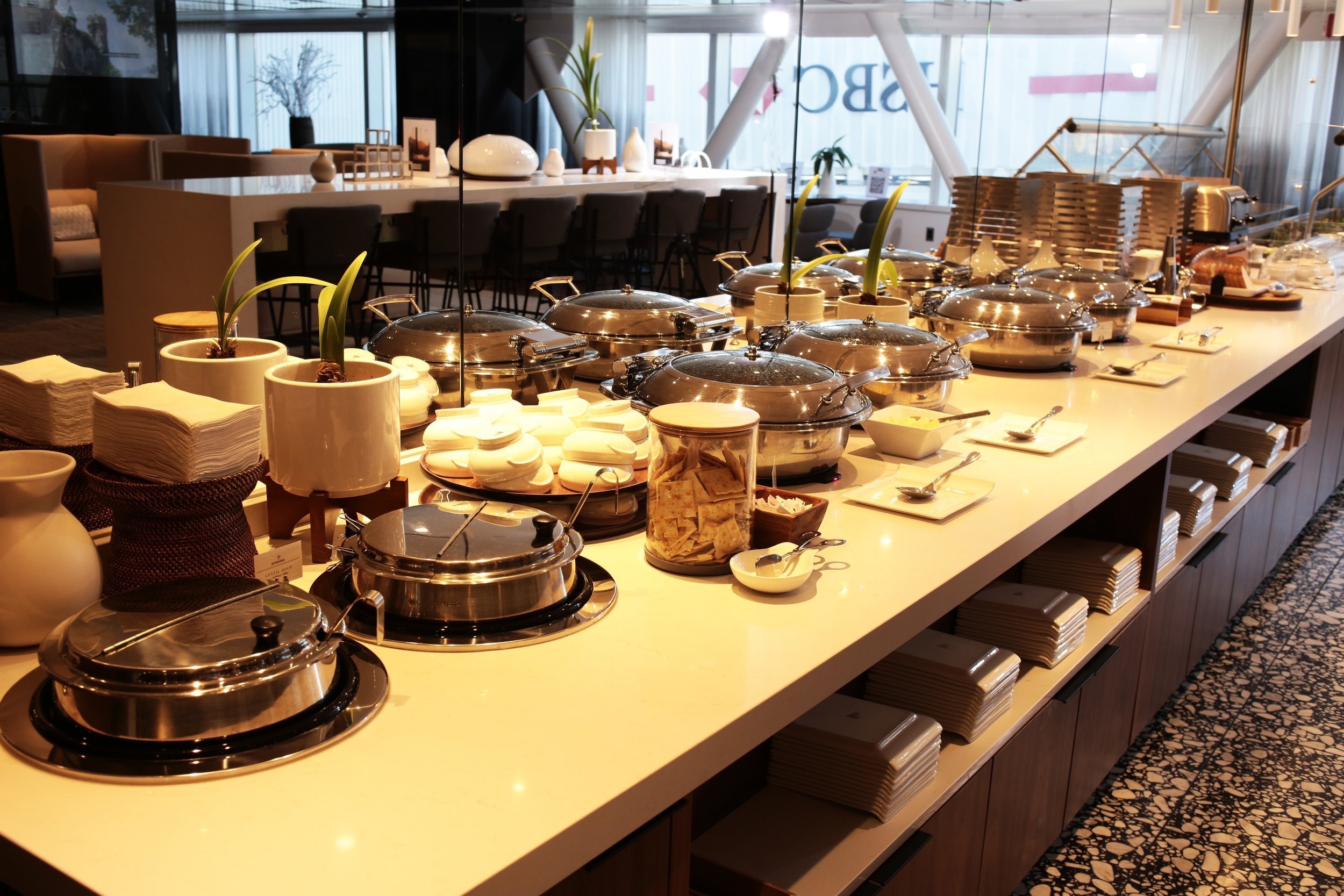 An assortment of hot food items under lids at the buffet in the T1 Primeclass Lounge at JFK Airport.