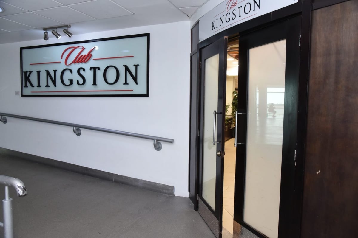 Entrance to Club Kingston Departure Lounge at Norman Manley International Airport in Kingston, Jamaica, featuring modern signage and welcoming double doors for premium travelers.