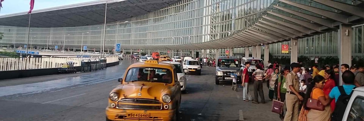 Kolkata Airport drop off or pick up zone with cars and people.