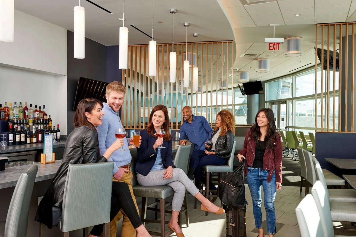Group of guests located around the bar in The Club LAS Terminal 1 D Gates