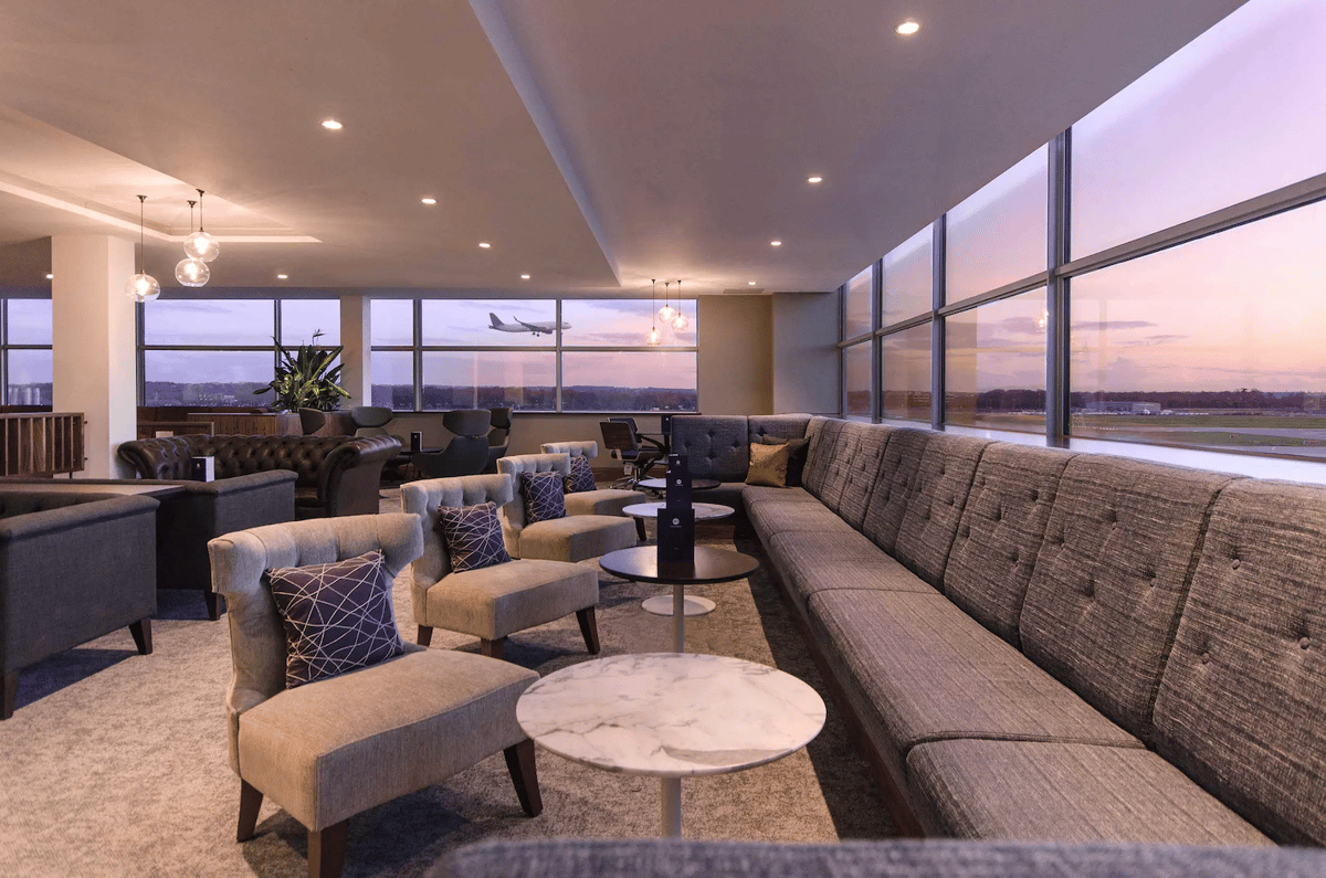 Image of the No1. Lounge at London Gatwick South featuring plush seating options including armchairs, extended sofas and leather couches. Floor to ceiling windows wrap around the room, with a plane suspended in the far window skyline.