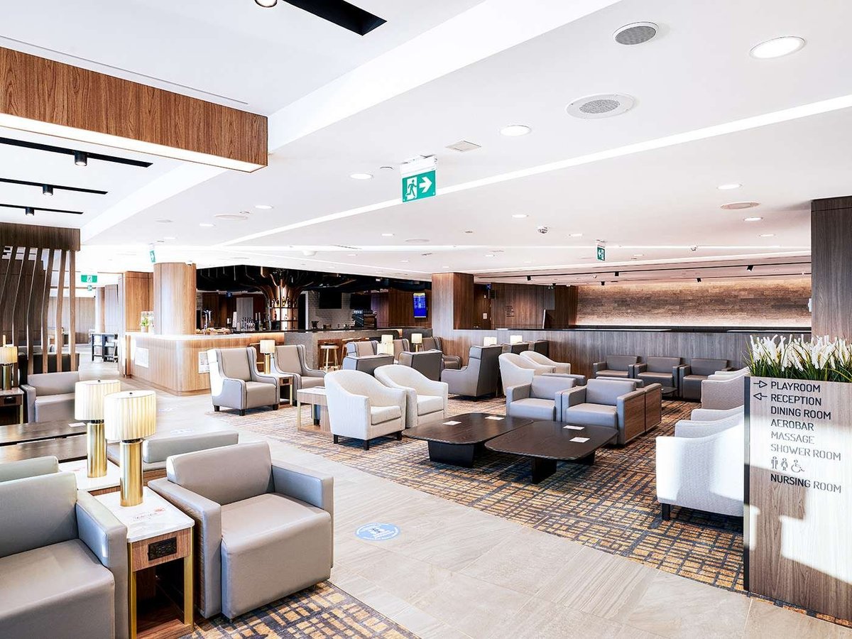 The T3 Plaza Premium Lounge at Toronto Pearson Airport featuring a variety of plush armchairs in neutral colours, giving the space a modern, contemporary feel. In the background a bar can be seen.
