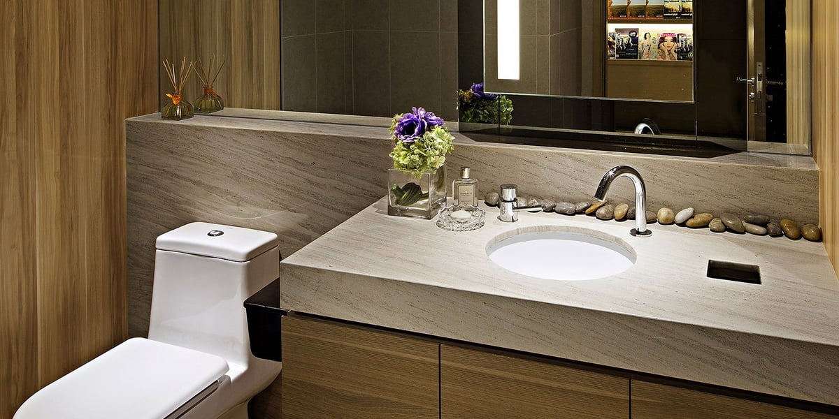 Bathroom in the plaza premium macau lounge. The bathroom features a sleek white toilet, and a matching countertop made of marble or stone. The sink is integrated into the countertop.