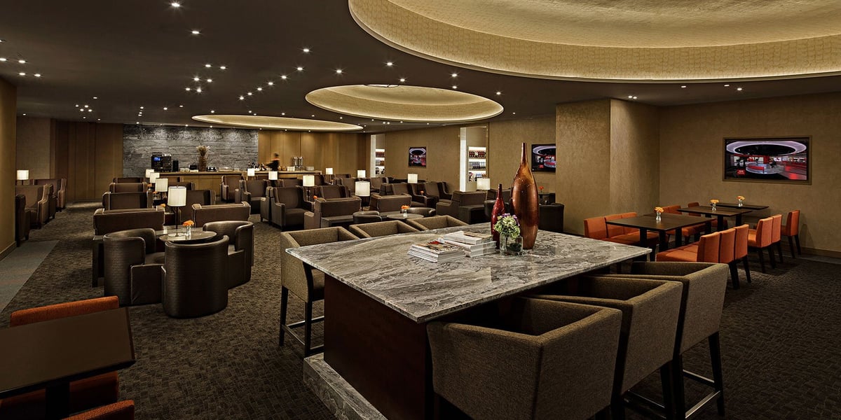 Seating Macau Plaza Premium Lounge. The lounge features comfortable, dark coloured armchairs, arranged in clusters around small tables. Decor is elegant and understated .jpg