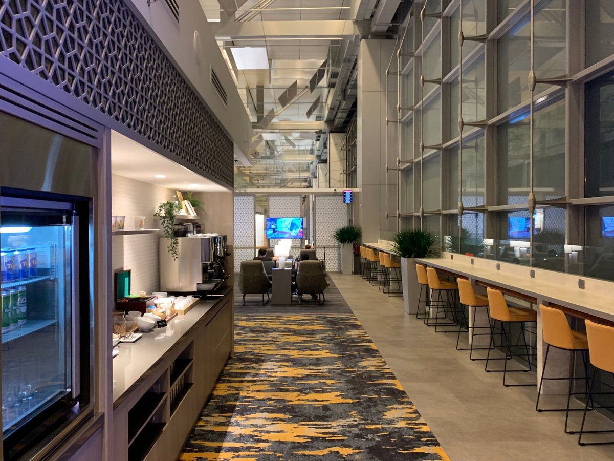 Buffet and seating area inside Marhaba Lounge at Singapore Changi Airport Terminal 3, featuring self-service counters, high chairs, and runway-facing windows.