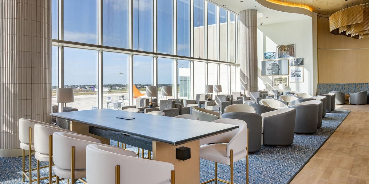 Bright and modern Plaza Premium Lounge at Terminal C MCO Airport with panoramic windows and elegant furniture.
