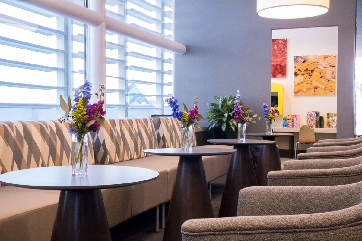 Chic lounge area in The Club at MCO Terminal A with patterned sofas and fresh flowers on tables.