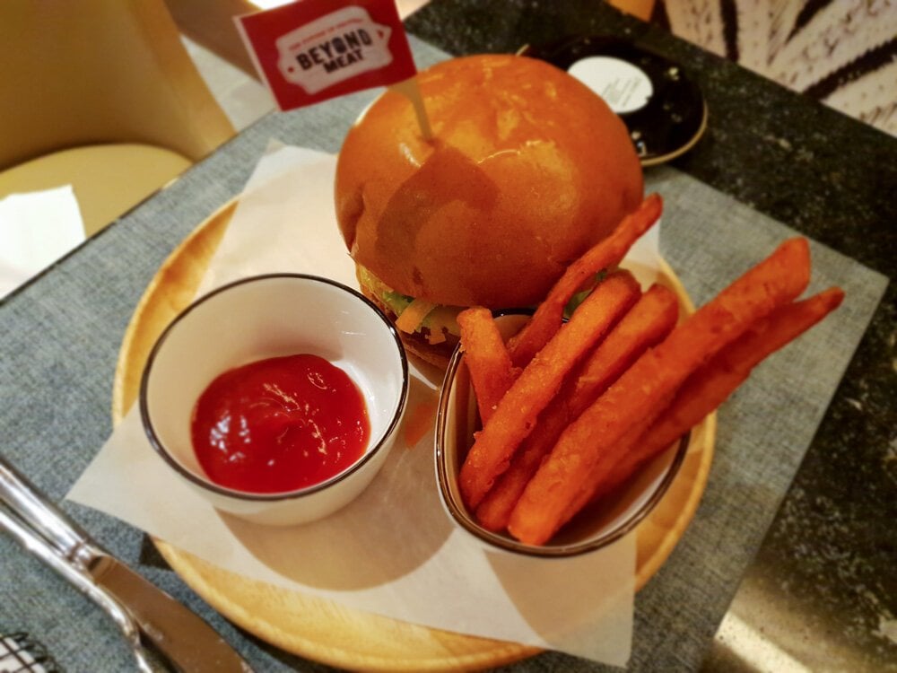 Food at the Plaza Premium First Lounge at Hong Kong International Airport featuring sweet potato fries, a beyond meat burger and tomato sauce in a small dish.