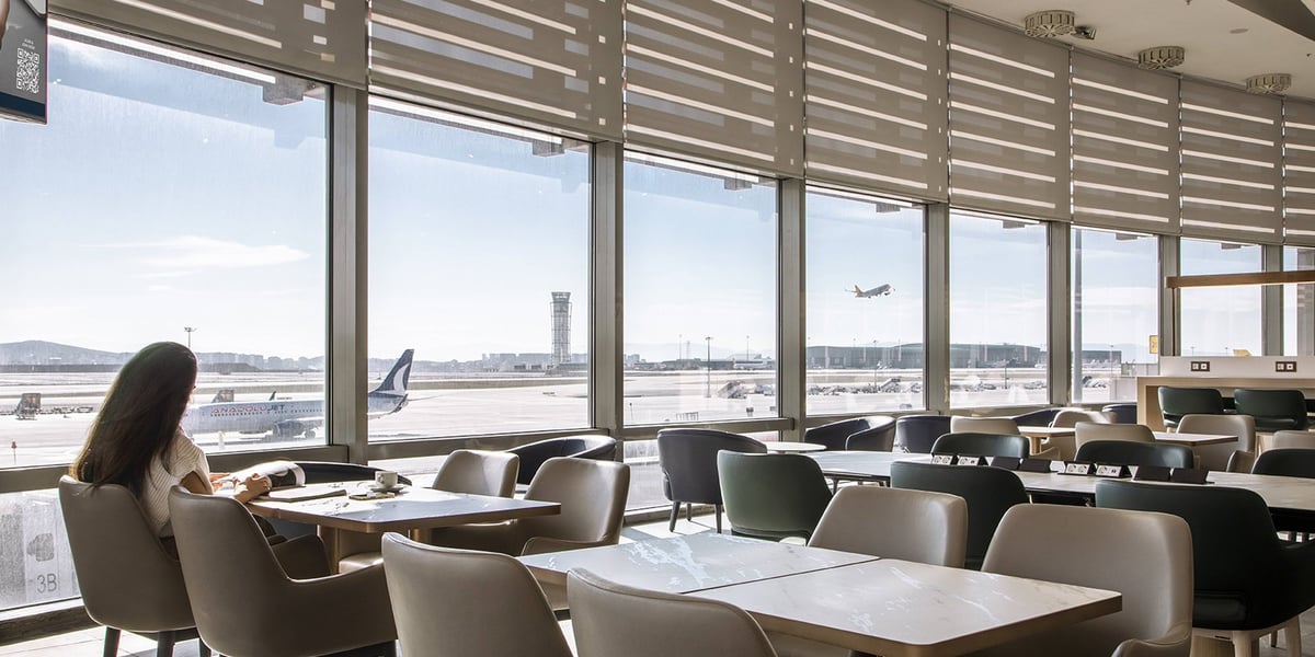 Dining area of the Marmara Lounge at SAW Airport. Marble tables are complimented by neutral coloured chairs and generous views of the runway, flooding the room with natural light.