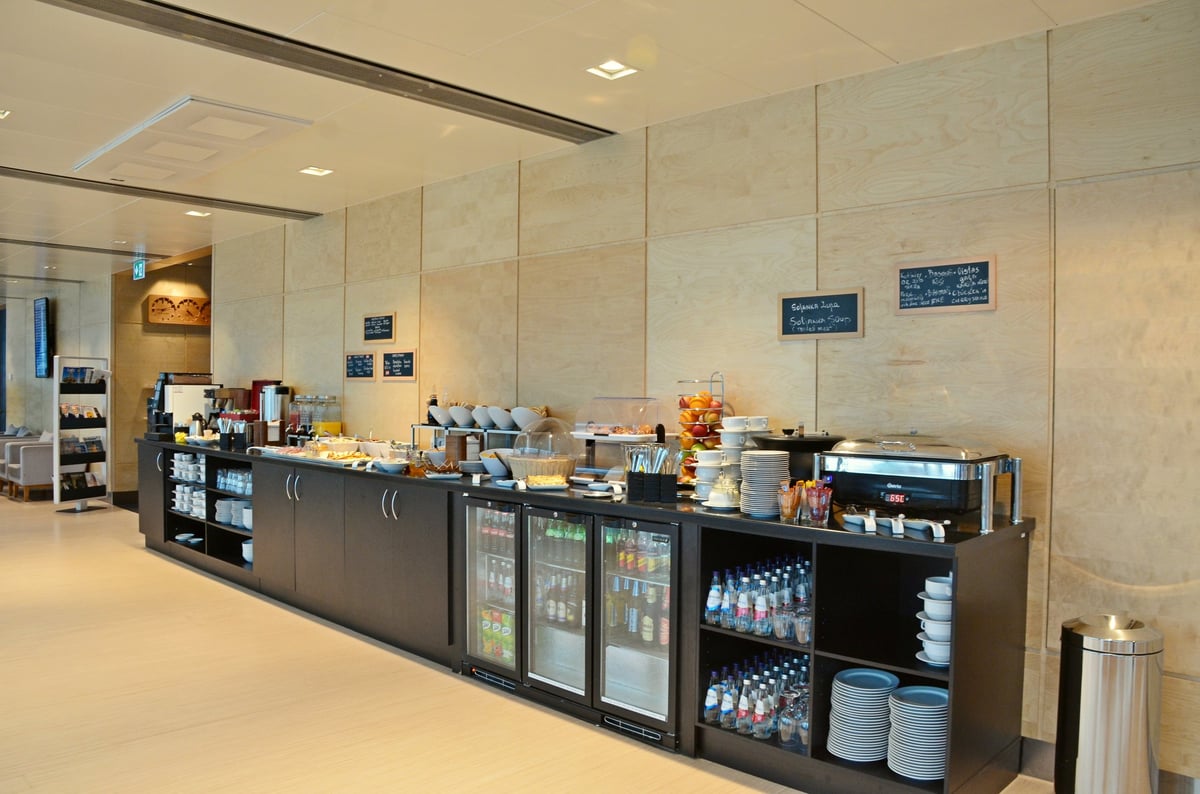 Buffet section of Primeclass Lounge at Riga Airport, with a selection of food and beverages for travelers.