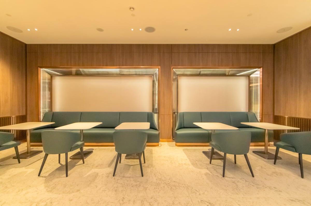 Modern dining booths and seating area inside The Private Room at Singapore Changi Airport, featuring elegant wooden paneling and soft lighting.