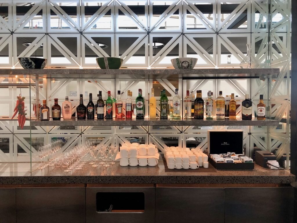 Selection of spirits, liqueurs, and wines at the bar in the Qantas Hong Kong Lounge, with wine glasses and coffee cups neatly arranged below