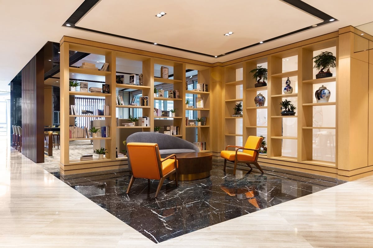 The reading and relaxation area inside Qingdao Jiaodong International Airport's Plaza Premium VIP Lounge, showcasing modern furniture against a backdrop of well-stocked bookshelves and elegant decor.