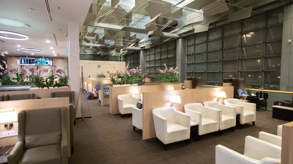Seating area inside SATS Premier Lounge at Singapore Changi Airport Terminal 3, featuring comfortable armchairs, work tables with power outlets, and modern lighting.