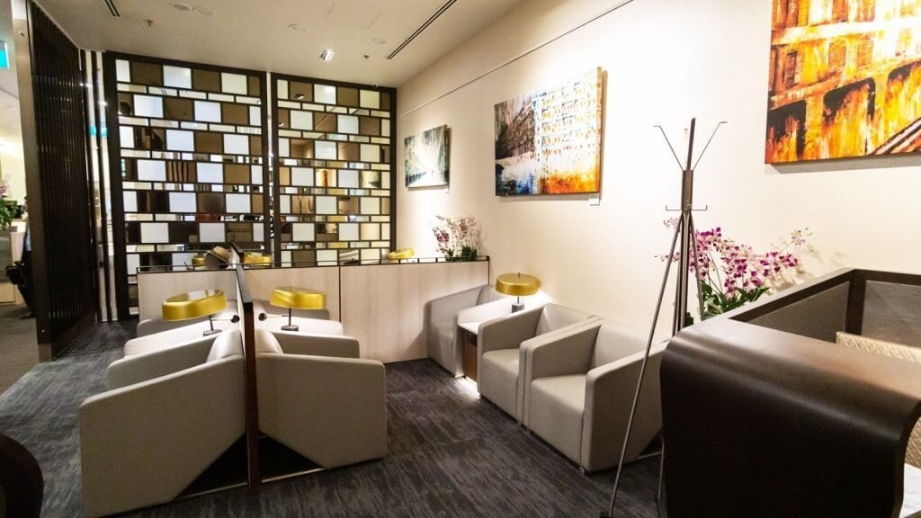 Stylish seating area inside SATS Premier Lounge at Singapore Changi Airport Terminal 3, featuring modern armchairs, artwork, and warm lighting.