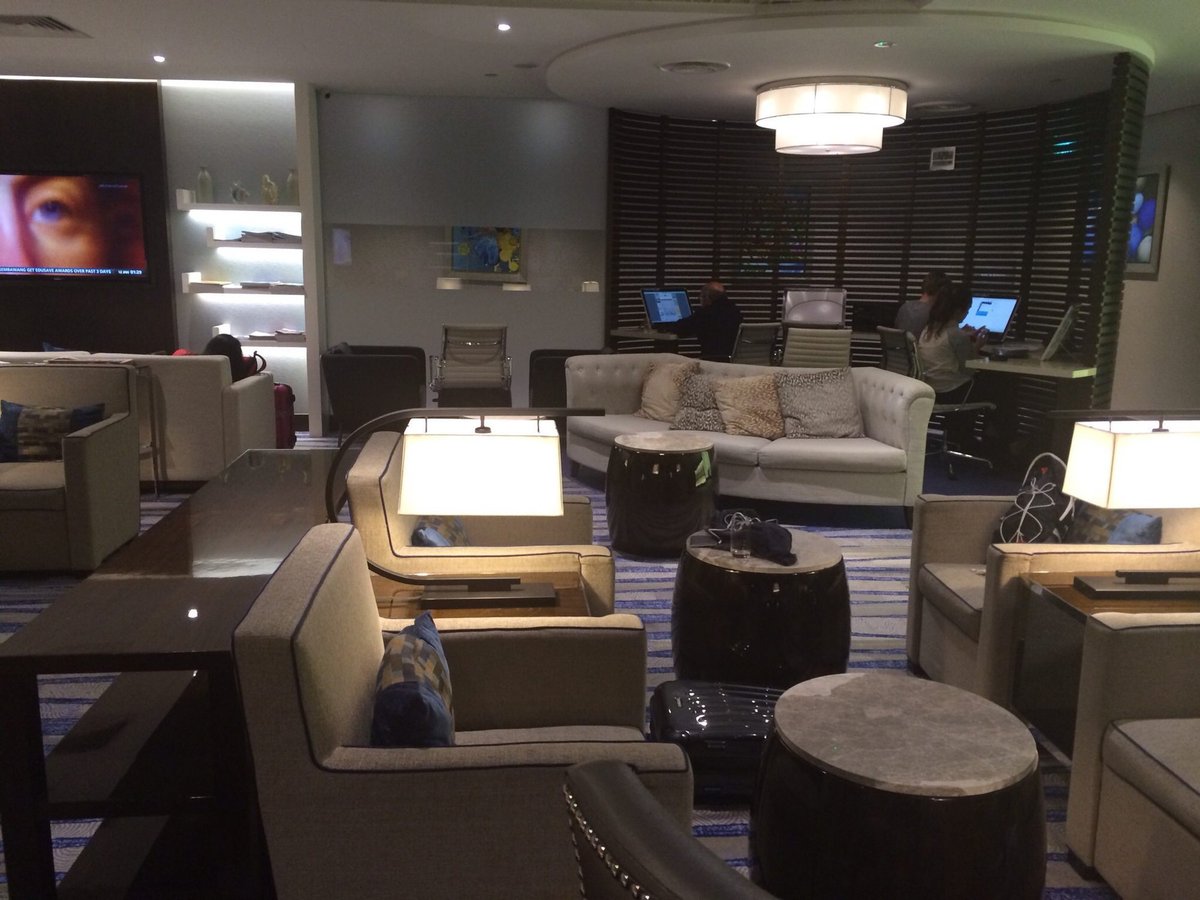 Seating and business area inside Ambassador Transit Lounge at Singapore Changi Airport Terminal 3, featuring sofas, workstations, and ambient lighting.