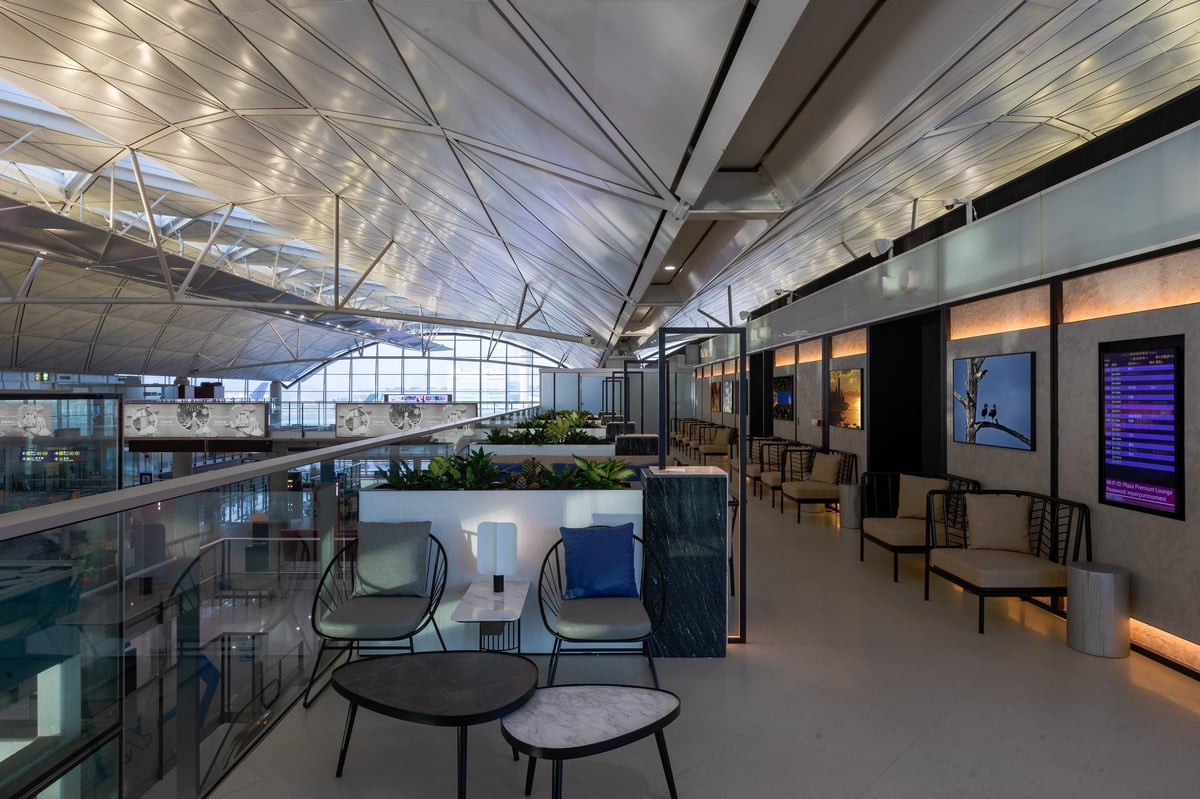 Lavazza coffee station at Plaza Premium Lounge West Hall in Hong Kong International Airport, featuring barista-style espresso setup, modern wood finishes, and window seating with tarmac views.