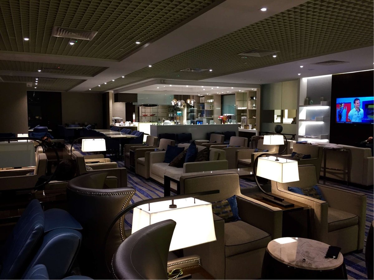 Wide view of Ambassador Transit Lounge at Singapore Changi Airport Terminal 3, featuring various seating options, ambient lighting, and buffet area in the background.