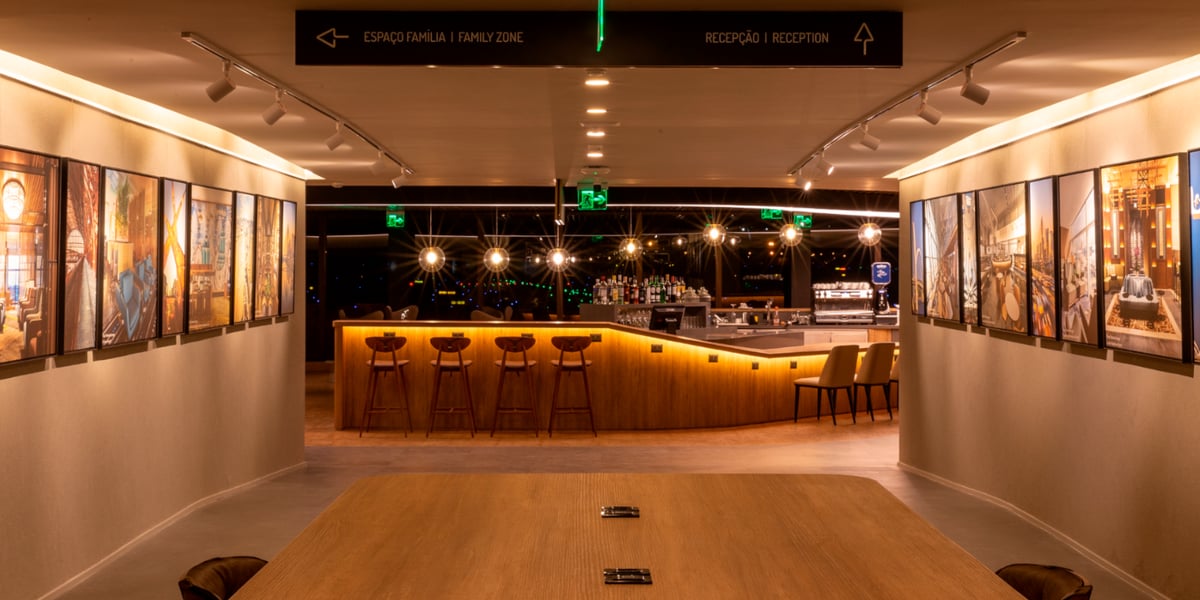 Modern bar area inside Plaza Premium Lounge at São Paulo Guarulhos Airport Terminal 2, featuring warm lighting, wooden decor, and framed artwork.