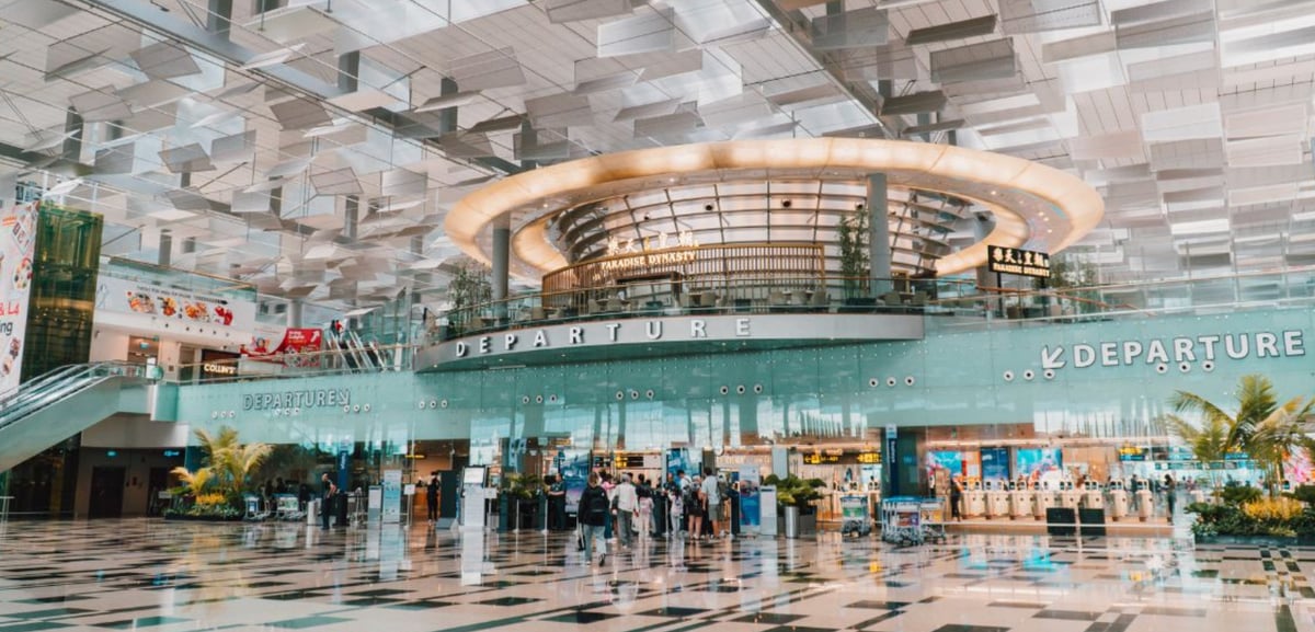 Departure hall at Changi Airport Terminal 3 with modern architecture, glass walls, and the Paradise Dynasty restaurant above the check-in area