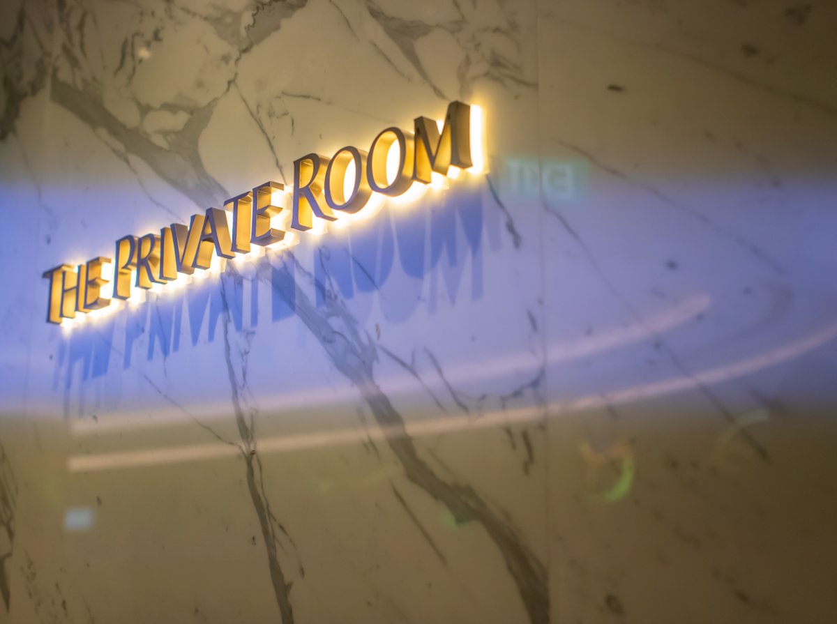 Backlit gold signage reading ‘The Private Room’ on a marble wall at Singapore Changi Airport, symbolizing luxury and exclusivity.