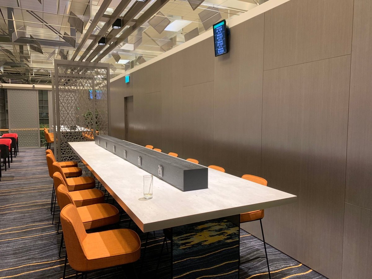 Work and dining area with charging outlets at Marhaba Lounge in Singapore Changi Airport Terminal 3, featuring long communal tables and modern seating.