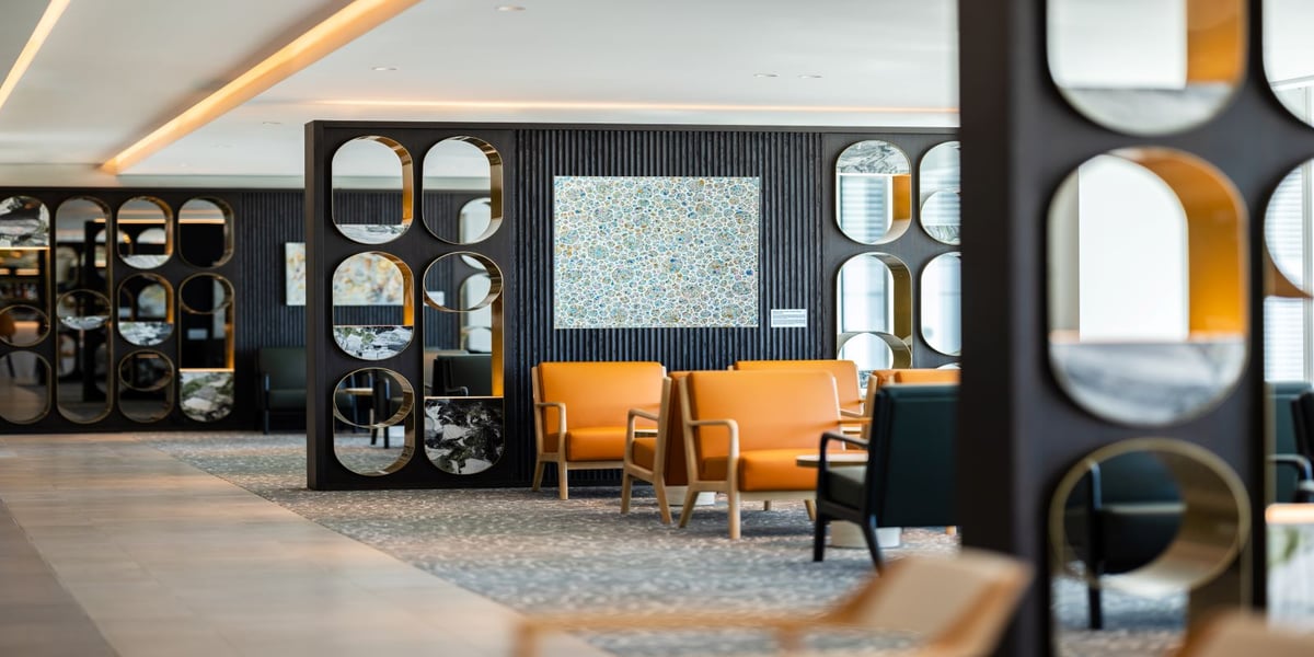 Plaza Premium Lounge at Adelaide Airport featuring orange and black leather chairs and abstract contemporary wall designs.
