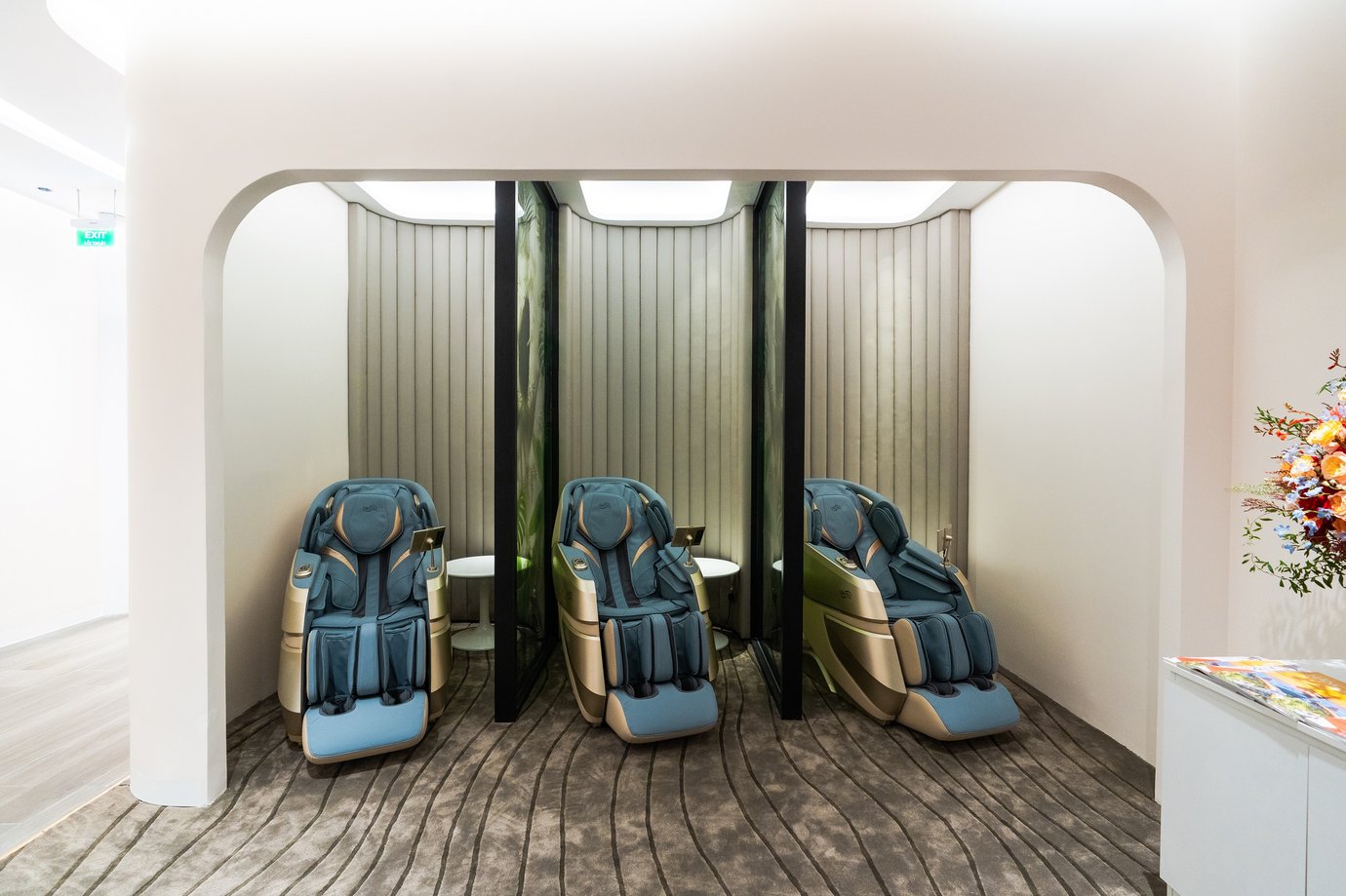 Private relaxation zone at Vanda Lounge, Da Nang International Airport Terminal 2, featuring three full-body massage chairs in softly lit alcoves with curved walls, textured carpet, and a serene modern design. Private relaxation zone at Vanda Lounge, Da Nang International Airport Terminal 2, featuring three full-body massage chairs in softly lit alcoves with curved walls, textured carpet, and a serene modern design.