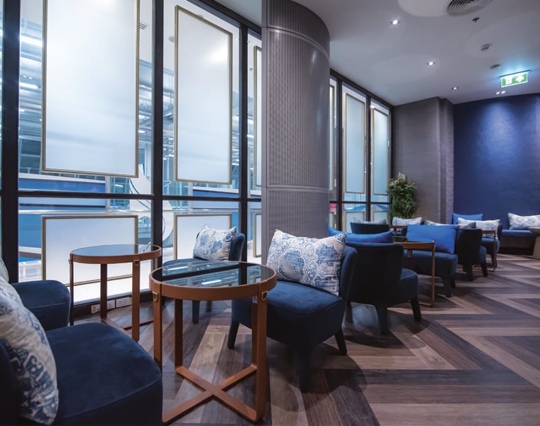 Bangkok Airways Blue Ribbon Lounge seating area at Bangkok Airport with blue armchairs and runway views.