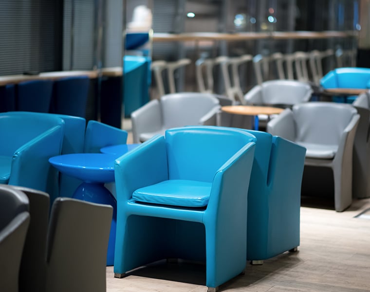 Boutique Lounge seating at Bangkok Airport with blue and grey armchairs, small round tables, and a softly lit, contemporary interior.