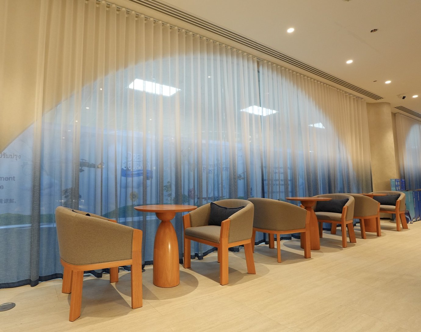 Bangkok Airways Boutique Lounge seating at Don Mueang Airport with armchairs and floor-to-ceiling curtains.