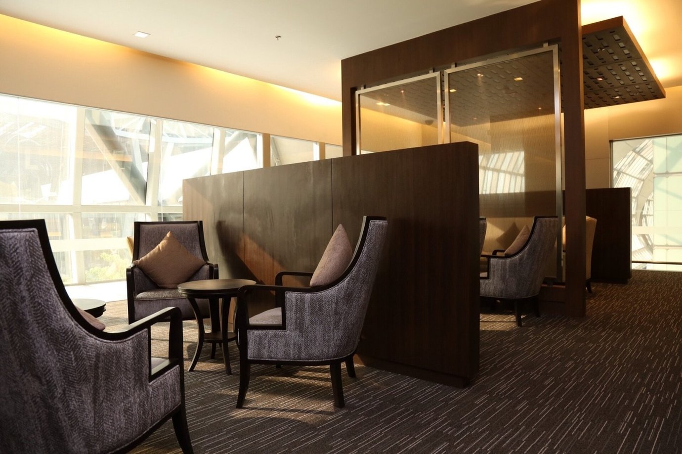 Private seating area inside the Miracle First and Business Class Lounge at Bangkok Suvarnabhumi Airport featuring pairs of high-back upholstered chairs with brown cushions, dark wooden tables, and semi-enclosed partitions Private seating area inside the Miracle First and Business Class Lounge at Bangkok Suvarnabhumi Airport featuring pairs of high-back upholstered chairs with brown cushions, dark wooden tables, and semi-enclosed partitions