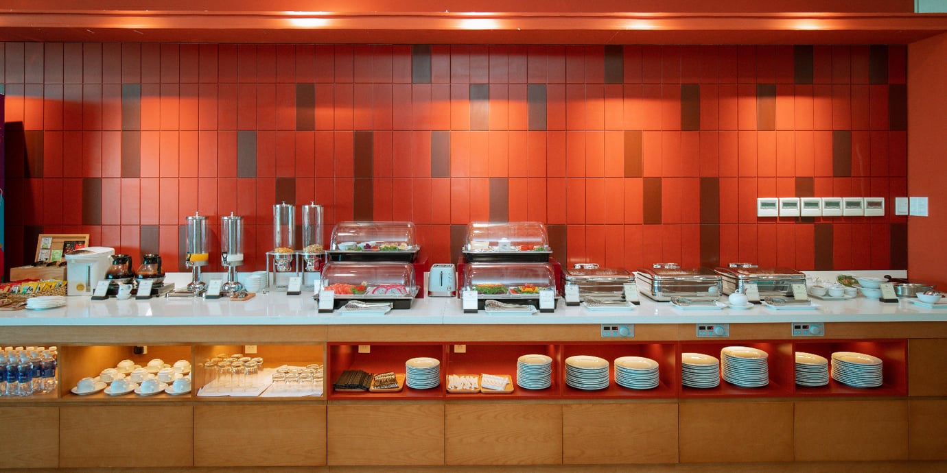 SH Premium Lounge Buon Ma Thuot Airport (BMV) buffet area featuring hot chafing dishes, covered cold plates, snack station, coffee and juice dispensers, and neatly stocked plates and glassware.