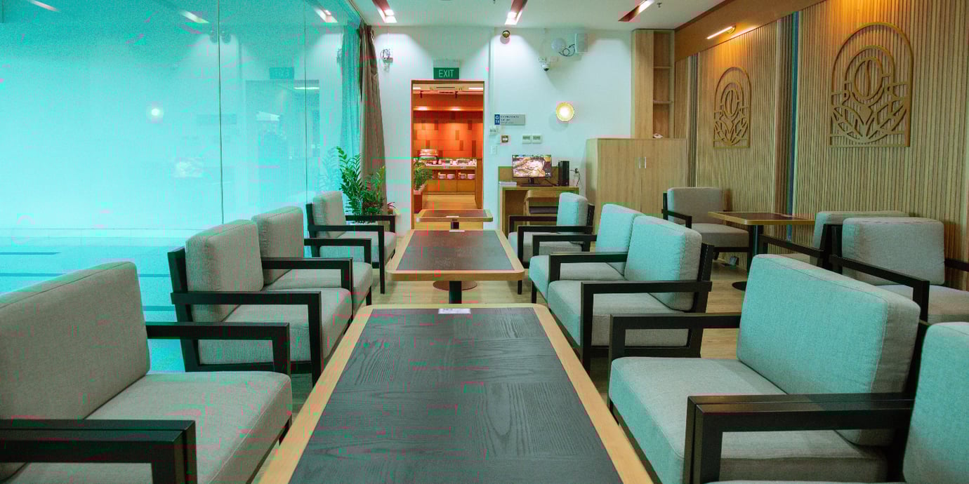 SH Premium Lounge Buon Ma Thuot Airport (BMV) seating area with modern armchairs and shared tables, frosted glass walls, warm wood accents, and easy access to the buffet area.