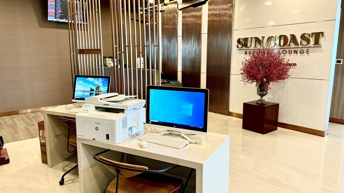 Business workstation inside Sun Coast Business Lounge at Cam Ranh International Airport Terminal 2, featuring desktop computers, printer, and modern workspace setup.