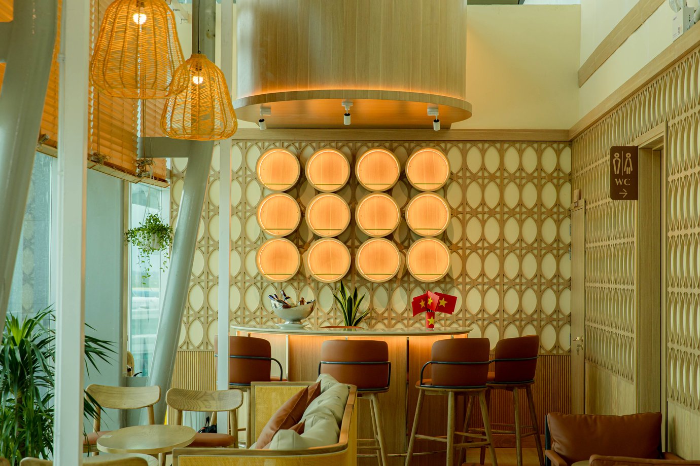 Bar counter with high stools at SH Premium Lounge, Cam Ranh International Airport Terminal 2, featuring modern wooden décor, warm lighting, and elegant rattan-inspired design.