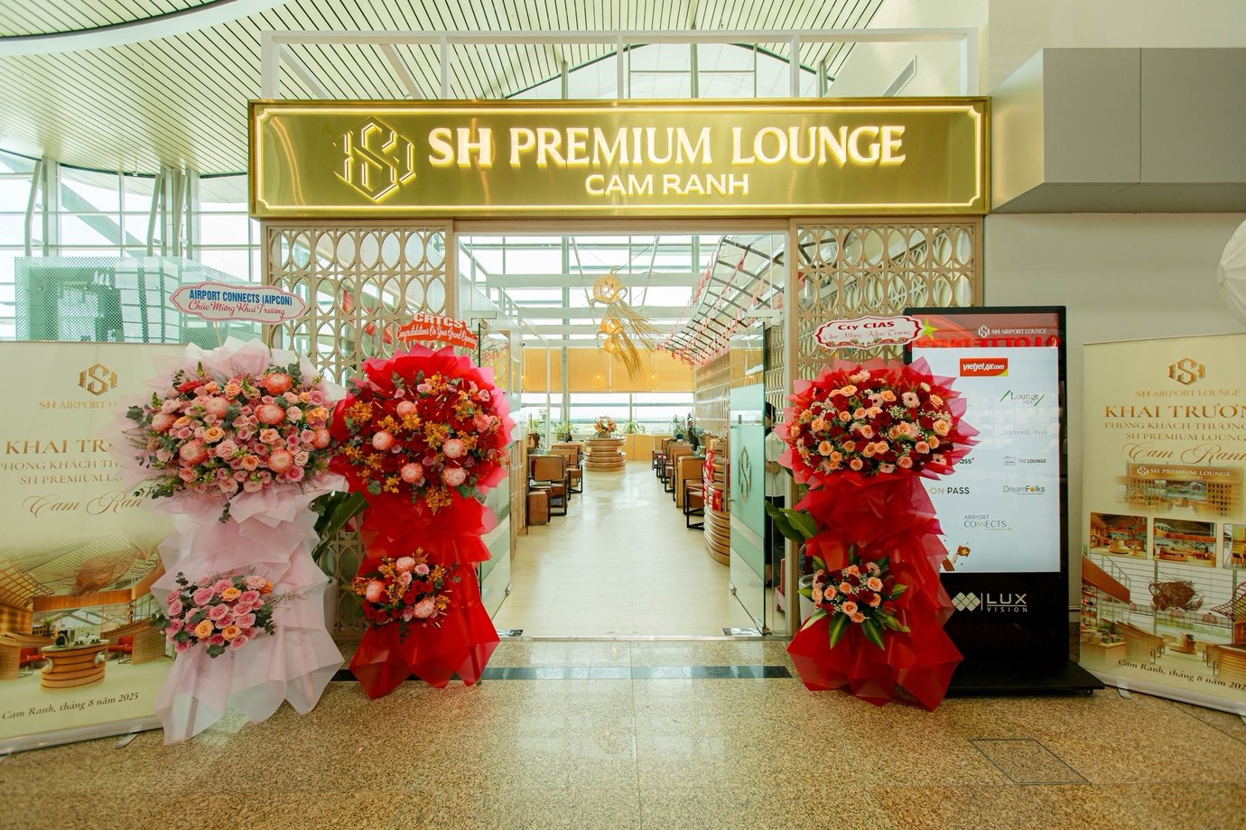 Entrance to SH Premium Lounge at Cam Ranh International Airport Terminal 2, decorated with floral arrangements and signage celebrating the grand opening.